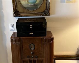This is a vintage console radio sitting under the framed painting of a vase of flowers.  We're not sure if it works, but it is a great conversation piece.