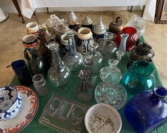 On this table are a number of glass vases, beer steins, and glassware.