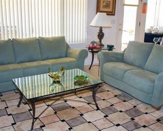 Blue couch with loveseat, glass coffee table, and decorative area rug