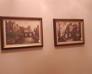 These two old village bridge scenes hang in the entry hall across from the brass and glass table.