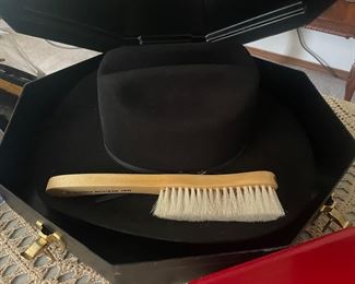 A table full of beautiful cowgirl hats, with hat boxes and brushes!