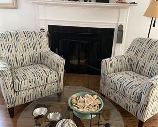 Pair of armchairs, round glass cocktail table with wood base, pottery and collections