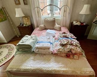 Full-size bed with wrought iron headboard flanked by a pair of vintage Craftique nightstands.
