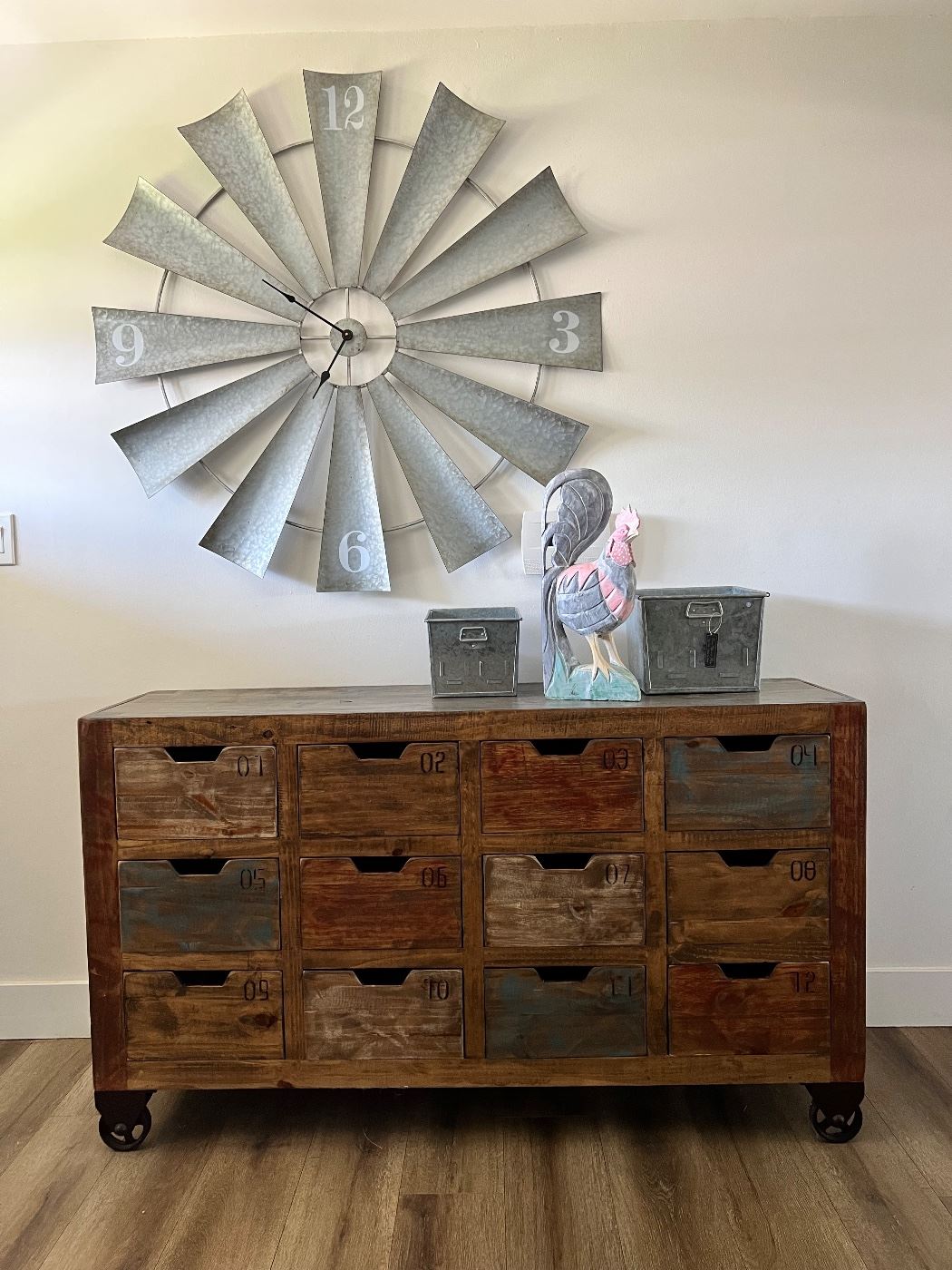 Love this rustic cubby cabinet with industrial wheels and the Windmill clock!