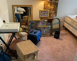spare room of pictures, queen bed, clothing, baskets, sewing rolling case, chess set etc