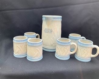 Blue and white stoneware.  Pitcher and six mugs with cattails.  Freeman Bros Furniture Corp., Collinsville, IL