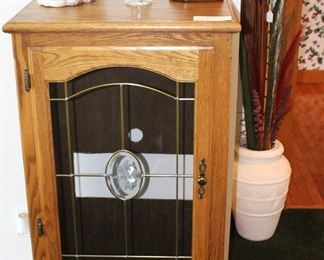 Oak cabinet with glass front door and shelves.