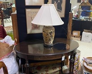 Glass topped oval table in front of three Japanese prints.