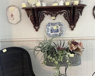 Carved wood shelf, painted china, wicker chair, planter stand and plants