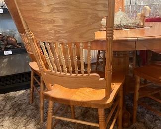 round, pedestal base oak table with pressed-back chairs
