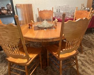 round, pedestal base oak table with pressed-back chairs