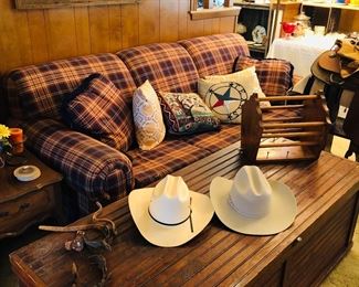 Nice plaid sleeper sofa, beaded board quilt box, spurs, and western hats.
