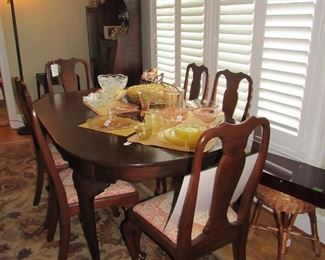 Queen Anne dining table with 3 leaves and 6 chairs, silver box, wicker stool, rug, yellow and pink Depression glass