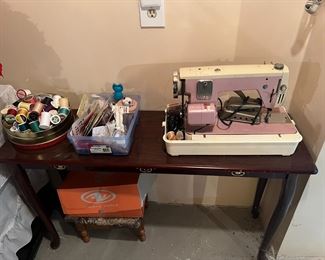 Pink sewing machine, thread, table, foot stool