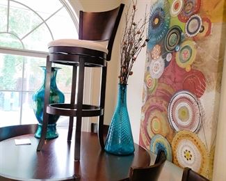 Bar height round table with 6 chairs. Blue glass decor and large canvas wall hanging