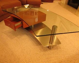 Item 3: Contemporary stainless, wooden, and glass top cocktail table with drawer. Brand name not found. 57.5” wide x 29” wide x 16.5” tall. PRICE: $650.00