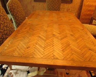 Item 4: Cellura Designs French Country-style pine trestle dining table with herringbone parquetry top, one 2’ leaf, and (8) side chairs. Table without the 2’ leaf measures 6’2” long x 42” wide x 29” tall. Each chair measures 21” wide x 23.5” deep x 42” tall. PRICE: $2,995