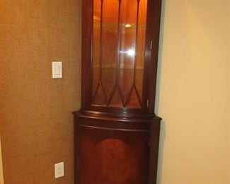 Item 12: Lighted bowfront corner cabinet with inlay. Not marked with brand name. 73” tall x 18” deep. 25” from each back corner to front. PRICE: $575.00