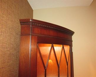 Item 12: Lighted bowfront corner cabinet with inlay. Not marked with brand name. 73” tall x 18” deep. 25” from each back corner to front. PRICE: $575.00
