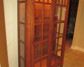 Item 16: Cherry Mission-style lighted curio cabinet. Brand name not found. 70.25” tall x 44” wide x 15.5” deep. PRICE: $750.00