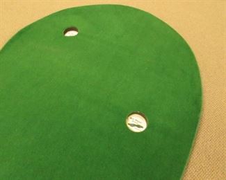 Item 48: “Big Moss Golf” 2-hole indoor putting green (mat). 12’ long at longest point x 4’ wide at widest point. Rolls for easy transport. PRICE: $125.00