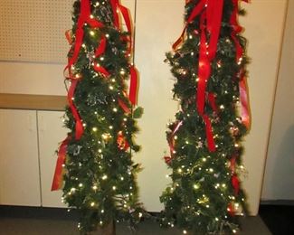 Item 62: TWO matching pre-lit pencil trees with bows, filler, and LED lights. Approximately 74” tall x 19” at widest point. PRICE: $150.00