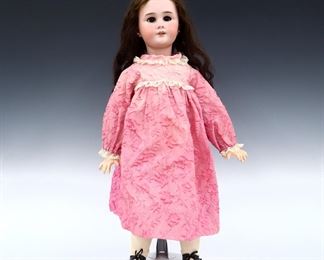 A turn of the century French Jumeau "Bebe" doll. Bisque socket head with Light Brown hair, sleep eyes, open mouth with teeth, pierced ears, real eyelashes and painted detail. On a jointed composite body, wearing a Pink floral silk organza dress with lace and leather shoes. Stamped "Jumeau" at neck with "R3923 / 2MK / 3.95" written and "DEP" impressed at head. Slight wear to paint, some wear and losses to composite, one damaged finger, wig coming unglued, fabric with fading. 25 1/2" long. ESTIMATE $300-400