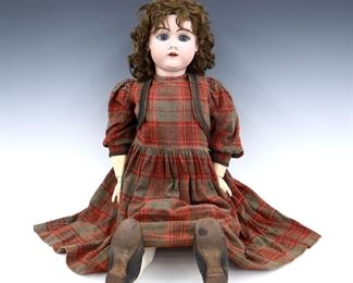 A turn of the century Henrich Handwerck doll. Bisque socket head with Brown hair, sleep eyes, open mouth with teeth, pierced ears and painted detail. On a jointed composite body, wearing a Red/Brown plaid dress and heeled leather shoes. Impressed "Germany / Handwerck" and "7" at neck, stamped "Henrich Handwerck / D.R. Patent No. 100279 / Germany" at torso. Some wear to paint, inner stringing loose, cracks to composite. 32" long. ESTIMATE $100-200