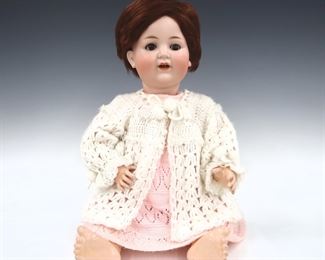 A turn of the century German mechanical talking doll. Key-wind mechanism at side, moves arm and talks. Bisque socket head with Brown hair, sleep eyes, open mouth with teeth, and painted detail. On a jointed composite body, wearing a Pink knit dress and White sweater. Impressed "Made in Germany" and "13 1/2". Mechanism not functioning, front torso panel does not stay attached, minor wear to paint, chip to one eyelid, some cracks to composite, clothing with some wear. 26" long. ESTIMATE $100-150