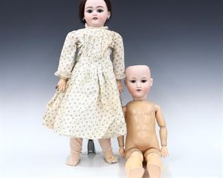 Two turn of the century German dolls. Bisque socket heads with sleep eyes, open mouths with teeth and painted detail on jointed composite bodies. Includes an unmarked doll with pierced ears wearing a White printed dress with lace, and an Armand Marseille 390N doll with without clothing or a wig. Marked doll impressed "Armand Marseille / Germany / 390N / A. 8 M.". Some wear to paint and composite, inner stringing a bit loose, fabric with some staining. Up to 24" long. ESTIMATE $100-150