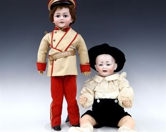 Two turn of the century German dolls. Bisque socket heads with sleep eyes, open mouths with teeth and painted detail on jointed composite bodies. Includes a baby with molded hair wearing a White silk blouse with Blue velvet pants and hat with booties, and a boy with pierced ears and Brown hair wearing a Tan/Red uniform with hat and leather shoes. Baby marked "151" and boy "DEP Germany / 11 1/2". Some wear to paint and composite, fabric with some wear and staining. Up to 25" long. ESTIMATE $100-150
