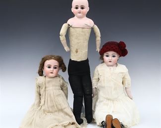 Three turn of the century German dolls. Full Bisque heads with stationary and sleeping eyes, open mouths with teeth and painted detail on jointed kid bodies with Bisque lower arms. Wearing various dresses and knit stockings, one without clothing. Each with impressed numbers at neck. Some wear to paint, one with repaired face, one lacks wigs, fabric with wear and staining, one arm detaching. Up to 25" long. ESTIMATE $50-100
