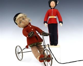 Two early 20th century British felted wool dolls. Stuffed felt heads with molded features and painted detail, on stuffed felt bodies. Includes an articulated Farnell Alpha newsboy on a mechanical bicycle, and a smaller British Royal Guard doll. Marked "Alpha Make, Made in England" on bike. Some wear, discoloration and minor losses. Up to 14" long and 13" high. ESTIMATE $100-200