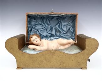 A 1930's Italian baby doll automaton music box. Wind-up mechanical wax doll in a paper covered box with hinged lid. Wear and minor damage, chip to one wax eyelid, some staining, bottom of box painted. 19 x 8 x 11 1/2" high overall, open. ESTIMATE $100-150
