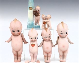 Six early 20th century Rose O'Neill "Kewpie" dolls. Each full Bisque, includes one holding a teddy bear with Blue bud vase, four early standing Kewpies, and a small hugging pair. Three with original stickers, standing Kewpies with "Rose O'Neill" signature at feet. Some wear to paint and surface, one with detached arms. 2 1/2" to 7" high. ESTIMATE $200-300
