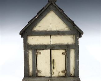An early 20th century Folk Art doll cottage or barn. Wooden cottage style house constructed from a shipping crate with a single room and shingled roof, features a White painted exterior with Gray trim, glass windows and barn front door, on an incorporated wooden base. Some wear and minor damage, shrinkage and wear to paint. 9 1/2 x 15 x 16" high overall.
