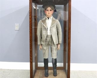 An early 20th century lifesize wax mannequin of a young boy, likely French.  Poured wax head with real Blonde hair, inset glass eyes, hand-painted lips, hair eyebrows and eyelashes on a cloth covered paper mache body with wooden articulated arms, wax hands, and Cast Iron boots.  Wearing a period wool suit with button up shirt and cap, presented in a molded Oak display case with glass sides.  Some wear and minor losses, wear to wax nose and hands, one finger repaired.  Mannequin is 47" high, case is 25 3/4 x 24 1/2 x 50 3/4" high overall.  ESTIMATE $800-1,200

