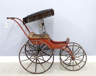 A 19th century Victorian Period baby carriage. Shaped wooden carriage with Red painted finish, upholstered seat and fringed leather parasol on an Iron frame with wooden spoked wheels. Wear and some damage, older repainting, repaired crack to seat. Approx. 58 x 22 x 44" high overall. ESTIMATE $200-300