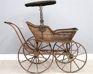 A late 19th century Victorian Period baby carriage. Wicker carriage with parasol on an Iron suspension frame with wooden spoked wheels. Wear and some damage, lacks cushion. Approx. 56 x 23 x 49" high overall. ESTIMATE $200-300