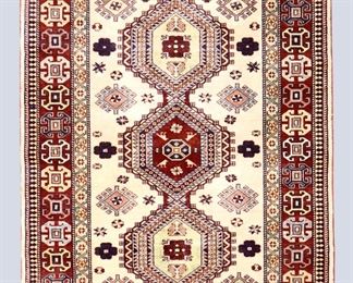 A 3.3 x 5.2' vintage Kazak rug. Multicolor geometric tribal design with three medallions on an Ivory field. Some wear and fading, a few stains to fringe. ESTIMATE $200-400