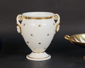 32	3 Pieces Vienna Style Porcelain	3 piece porcelain lot. Compote, cobalt with gilt, 2 3/4"H x 7 1/8"W including handles; jug, cobalt with gilt, 6"H; vase, gilt decoration with figural handles, 6"H. All with blue Royal Vienna style "beehive" shield marks. Chip, line and repair to spout of jug.
