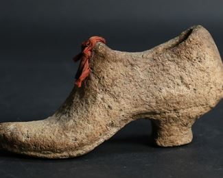 99	Macerated U.S. Currency Shoe Sculpture	A small shoe shaped sculptural souvenir comprised of macerated U.S. currency. On the sole of the shoe there is a torn label declaring the following: "Made of U.S. National Greenbacks, redeemed and macerated at the U.S. Treasury. Estimated $5,000." The piece measures 2 1/2" H x 1 5/8" W x 5 3/8" D. There is minor cracking and loosening of the fibers on the interior of the shoe, as well as some all over discoloration.
