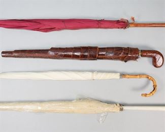 103	4 Umbrellas & Parasols	"Lot of 4 umbrellas and parasols. Painted wood parasol with figural porcelain handle, 38 1/4""; parasol with bamboo form handle, 26 1/2""L; red parasol with wooden handle, 37""L; umbrella with alligator handle and cover, 25 1/4""L.

Fraying, tears and staining to porcelain handled parasol, porcelain handle repaired at head, neck and body and large chip to end, scratches and paint loss; bamboo parasol staining to fabric; red parasol staining to fabric, missing jeweled handle; leather umbrella scratches to handle, tears to cover and lining of cover throughout, staining to umbrella fabric.

Bamboo and red parasols Christie's New York, sale 9590, October 20, 2000, the Di Portanova Collection; all collection of a prominent Connecticut family."
