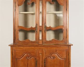 107	French Provincial China Cabinet	"French Provincial china cabinet. 19th century. Upper section with two glass doors with linen-lined interior with two glass shelves, lower section with one shelf and two scroll-carved doors. Later 21st century lock hardware on both sets of doors. No keys are included. Crack to glass on right door of upper section of cabinet. Gouges and scratches to top lower section of cabinet. Marks, scratches, and scuffs to wood throughout sides and front of cabinet. Nicks and chips to wood on feet of cabinet. White paint mark to wood on right side of cabinet. Shelf in lower section of cabinet is separated and split into two pieces. Remnants of glue to wood on separated shelf. Repairs and losses to wood molding on left side of crown. Molding on left side of crown is very loose. Slight splits and separations to wood on back paneling on lower section of cabinet. 

52"" W x 19"" D x 93 3/4"" H. 154 lbs."
