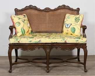 116	Louis XV Provincial Style Settee	"Louis XV Provincial style settee. 20th century. Heavily carved frame, caned back, later upholstery and cushions. Chips, scuffs, marks, nicks, and wear throughout wood of settee, especially along arms and legs. 

46 1/2"" W x 23 1/2"" D x 38 1/2"" H. 46 lbs."
