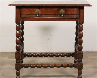 119	William and Mary Tavern Table	"William and Mary tavern table. Turned knobby legs and stretcher, one drawer, brass teardrop pulls. Scratches, marks and wear throughout top of table. Splits to wood on top of table. Nicks and marks to wood throughout turned legs and stretcher. Small loss to wood on joinery of front left leg and stretcher. Tape residue to wood on back of table on apron and on back stretcher. Split to wood on drawer. Loss to wood on back left corner of top of table. Slight warping to top of table.

28 7/8"" W x 19 7/8"" D x 27 1/8"" H. 32 lbs.

"
