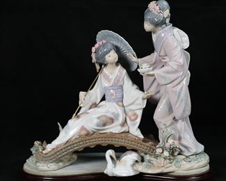 162	Lladro Porcelain Figure Group Springtime in Japan	Lladro porcelain figure group 1445, Springtime in Japan. Blue Lladro mark to the underside. 13 1/4"L x 11 3/4"H. Chips to flowers in standing woman's hair, discoloration to fabric on wooden stand.
