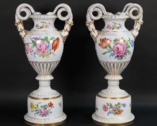 168	Pair of Meissen Style Porcelain Urns	Pair of Meissen style porcelain urns / vases. Figural serpent handles, hand painted floral and gilt decoration. Unsigned. Each 20 3/4"H to top of handles. Losses to gilt decoration on upper and lower rims of bases on both, small scratch to floral decoration on one, some discoloration to the interiors of both, minor flake to the underside of one.

