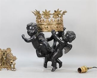 181	After Bernini & Nelli Cherub Ceiling Fixture	After Gian Lorenzo Bernini and Alessandro Nelli, cherub hanging lamp. Patinated and gilt bronze. 12 1/2"H. One wing cracked and chipped, crown bent and cracked on one side, minor scratches and losses to patina. Ceiling cap, socket and partial chain present.
