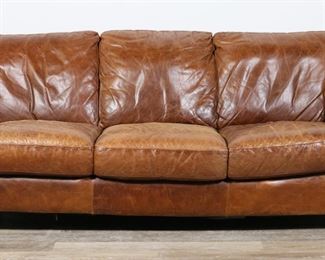 261	Natuzzi Style Italian Leather Sofa	"Leather sofa in the style of Natuzzi. Italian, 21st century. Six fixed seat and back cushions and four wooden feet. As is, with wrinkling, wear, scratches, scuffs, and marks throughout entirety of leather of sofa. Staining to leather on seat cushions on sofa. Original labels are missing. Tears to lining on underside of sofa. Construction of seating is sunken 1 1/2"" on front right side on sofa. Scuffs and marks to feet.

90"" W x 39"" D x 35"" H. 132 lbs."
